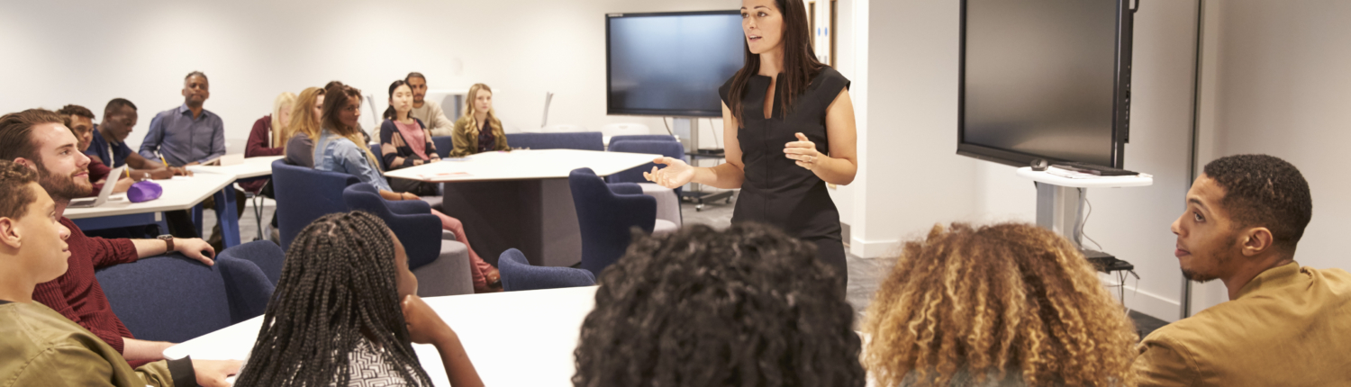 Female teacher addressing university students in a classroom